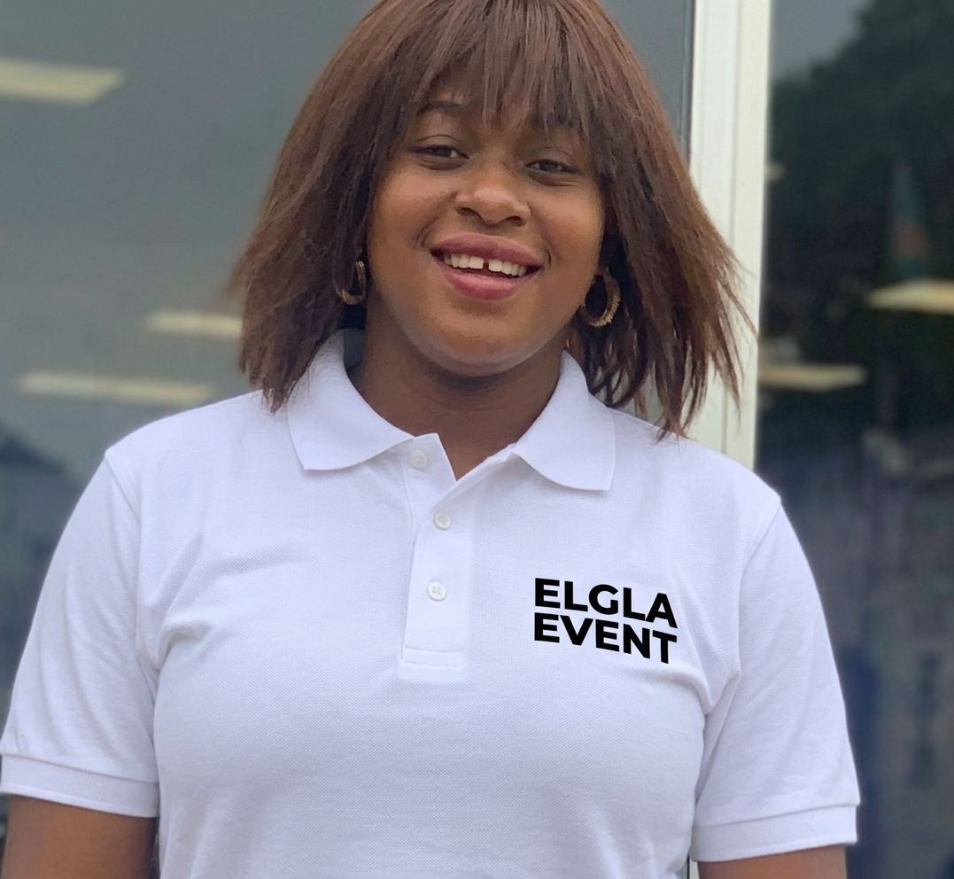 Smiling woman wearing a blue ELGLA EVENT polo shirt standing outdoors